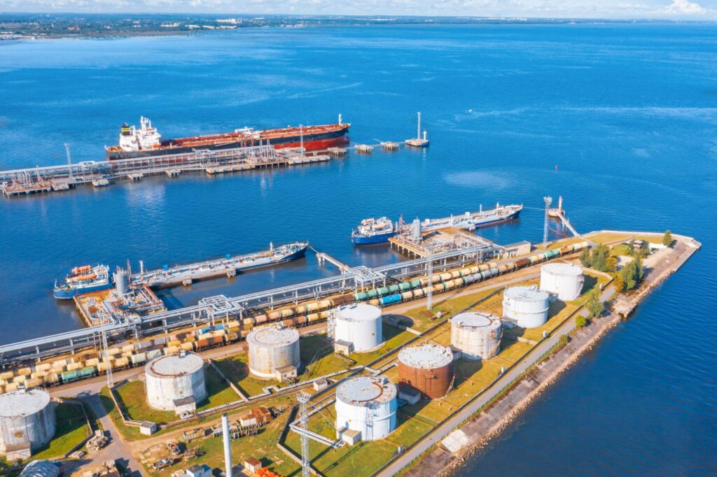 Aerial view large port oil loading terminal with large storage tanks. Railway infrastructure for the delivery of bulk cargo by sea, using pump station in ship tanker for transportation and delivery.